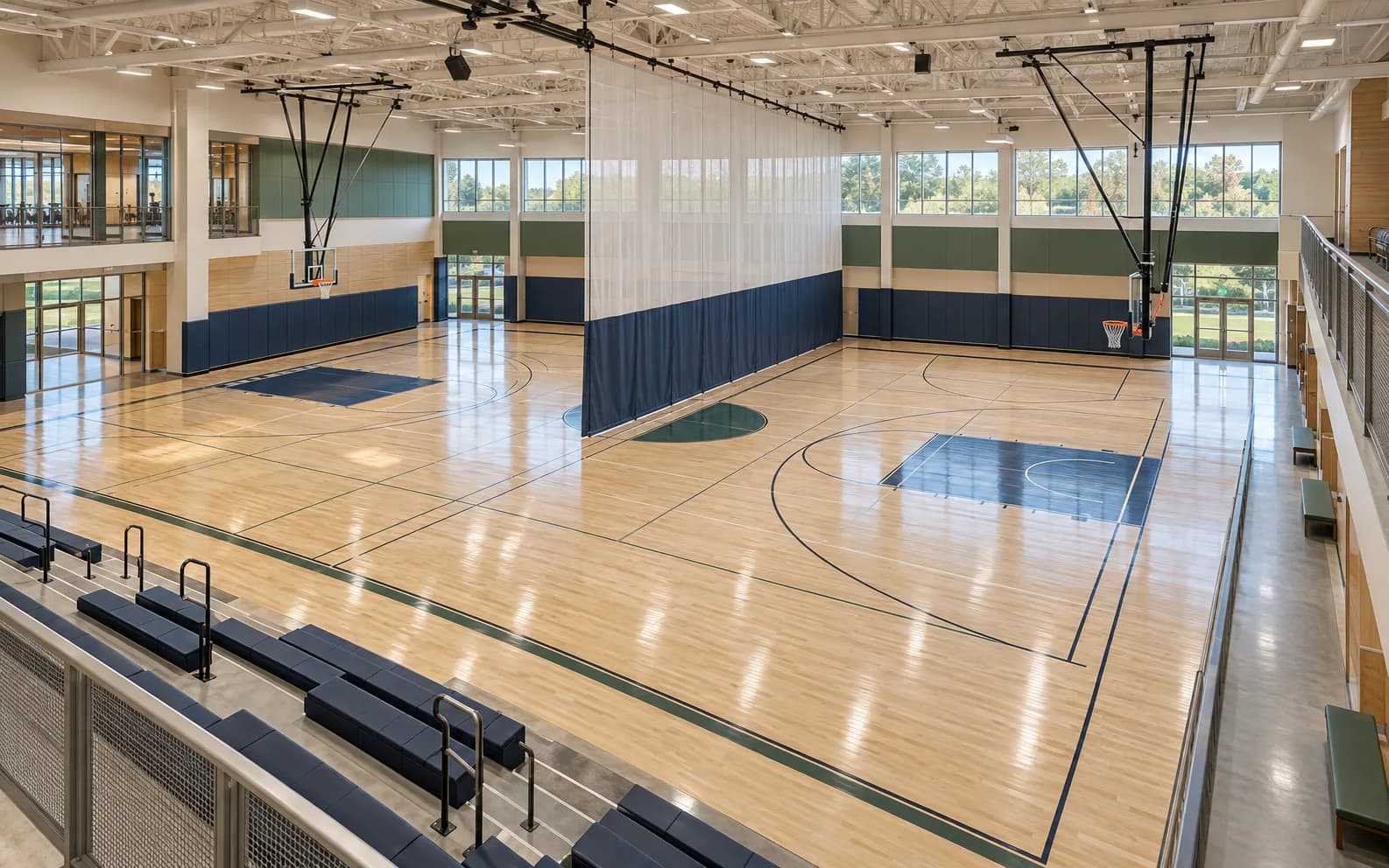 Two-court recreation center with divider curtain and compact bleachers